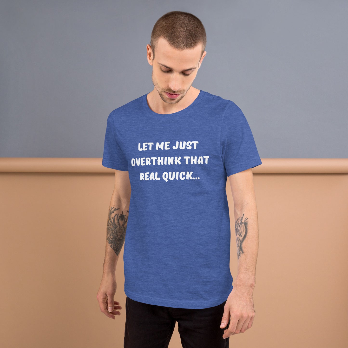 Young man with tattooed arms wears a blue tee shirt that reads "Let me just overthink that real quick..."