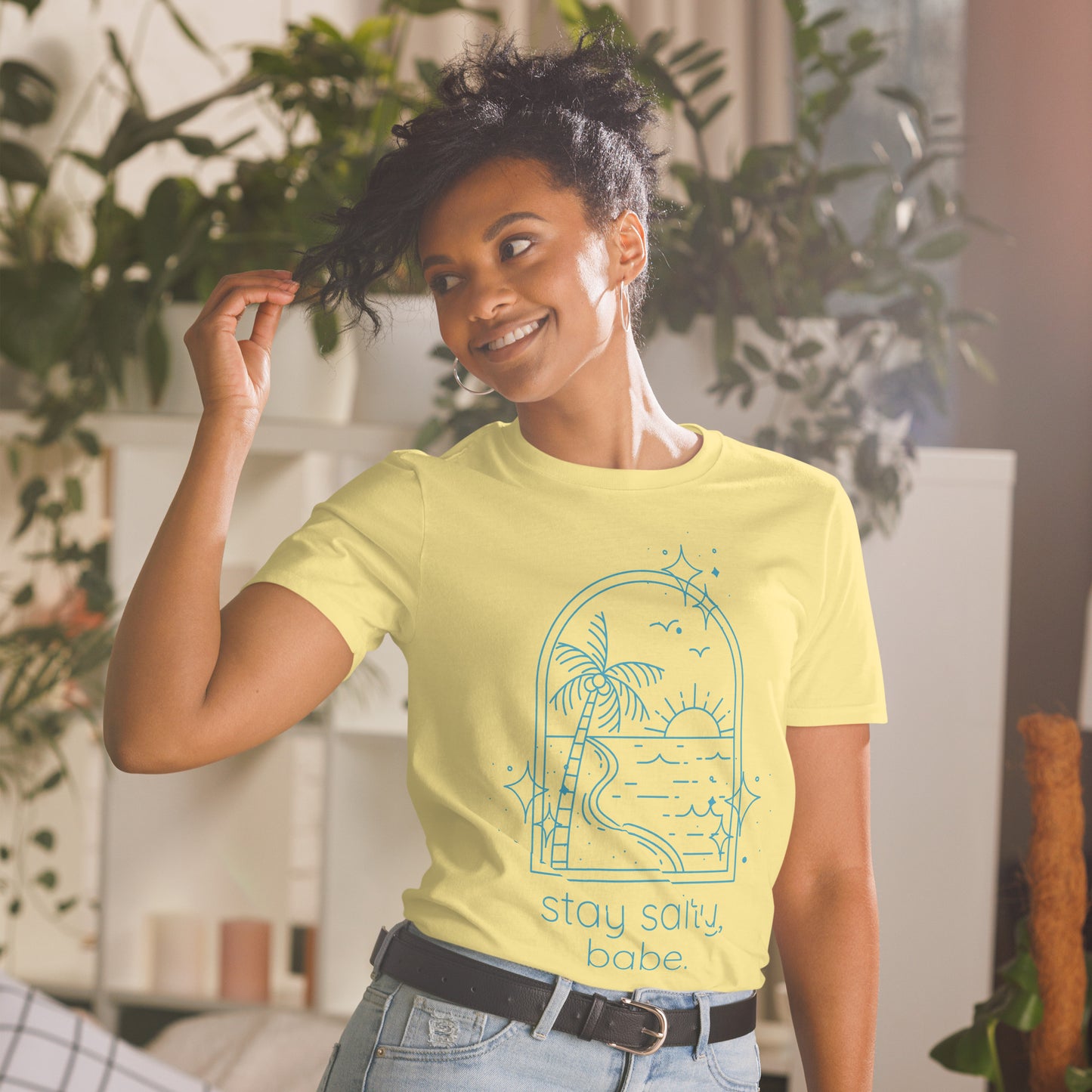 Woman wearing soft yellow “Stay Salty, Babe” beach graphic tee styled with jeans.