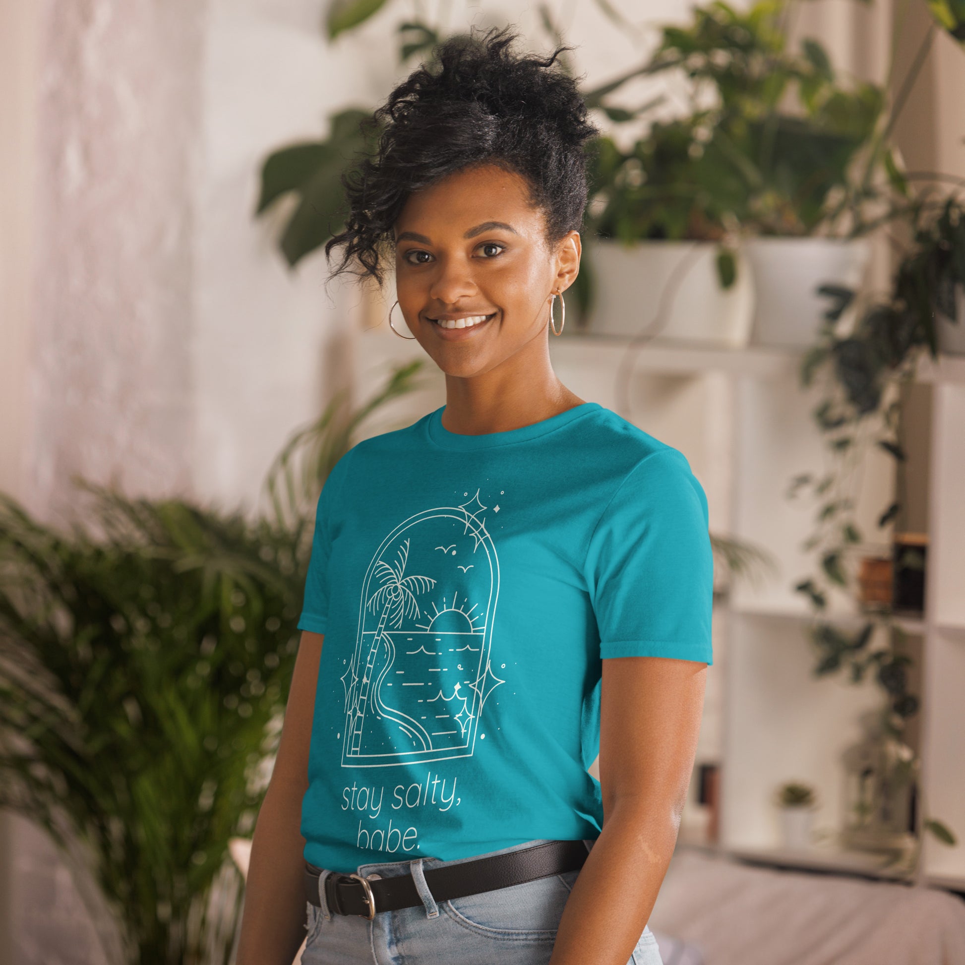 Tropical blue "Stay salty, babe" tee shirt styles on model with jeans and hoop earrings. 