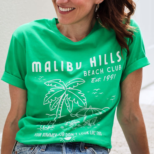 Woman wearing a nostalgic Malibu Hills Beach Club Graphic Tee in kelly green.