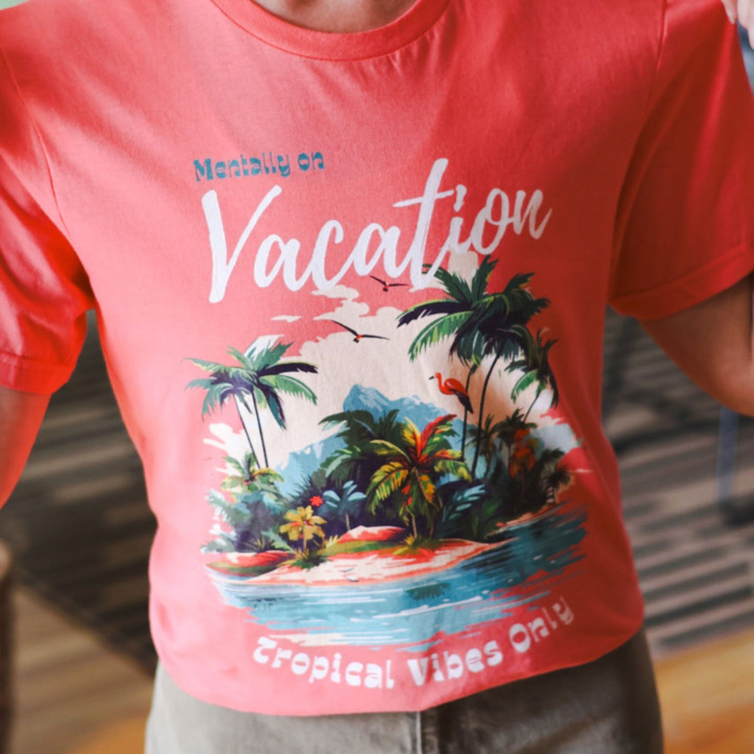 Coral t-shirt with tropical island graphic and text 'Mentally on Vacation' and 'Tropical Vibes Only'.