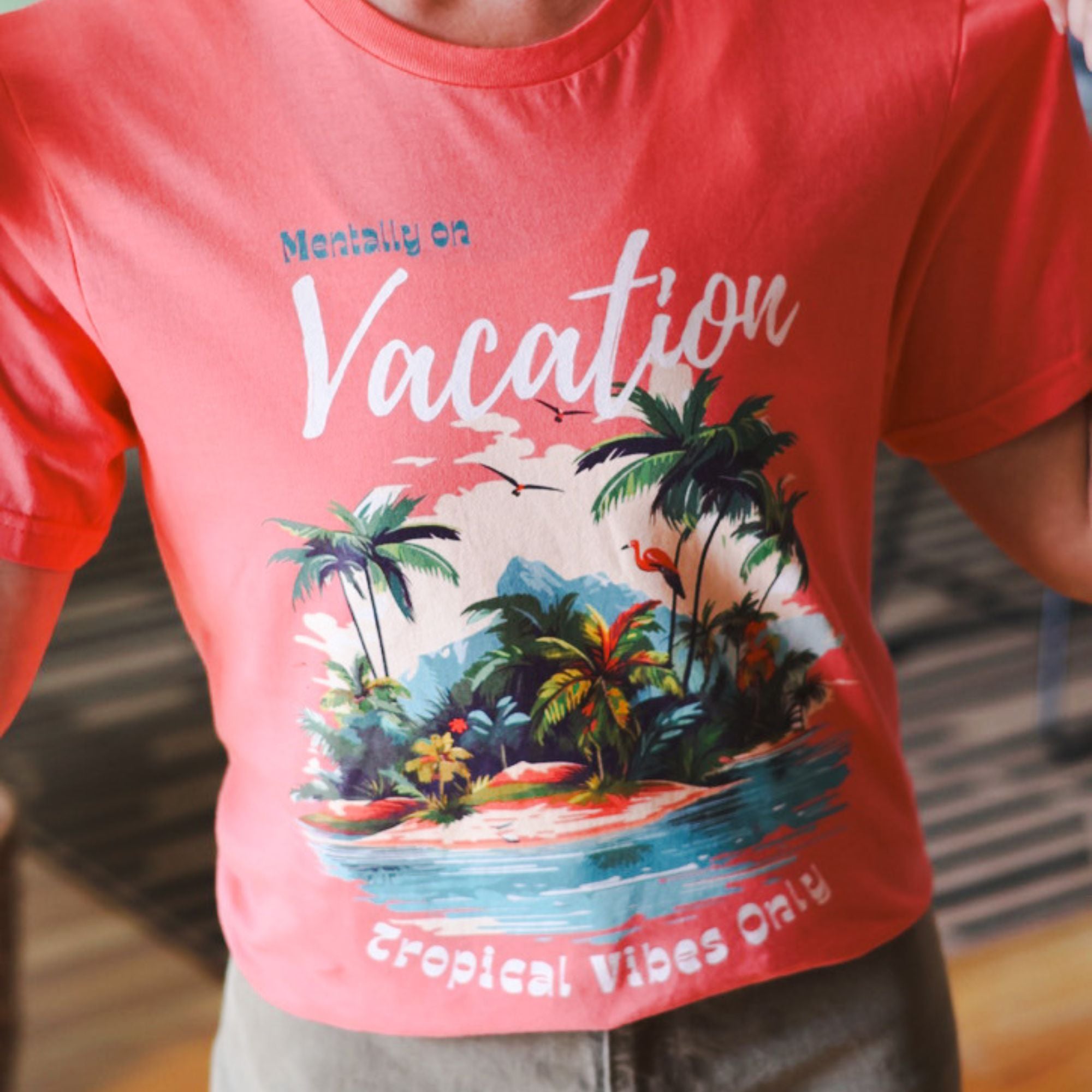 Coral t-shirt with tropical island graphic and text 'Mentally on Vacation' and 'Tropical Vibes Only'.