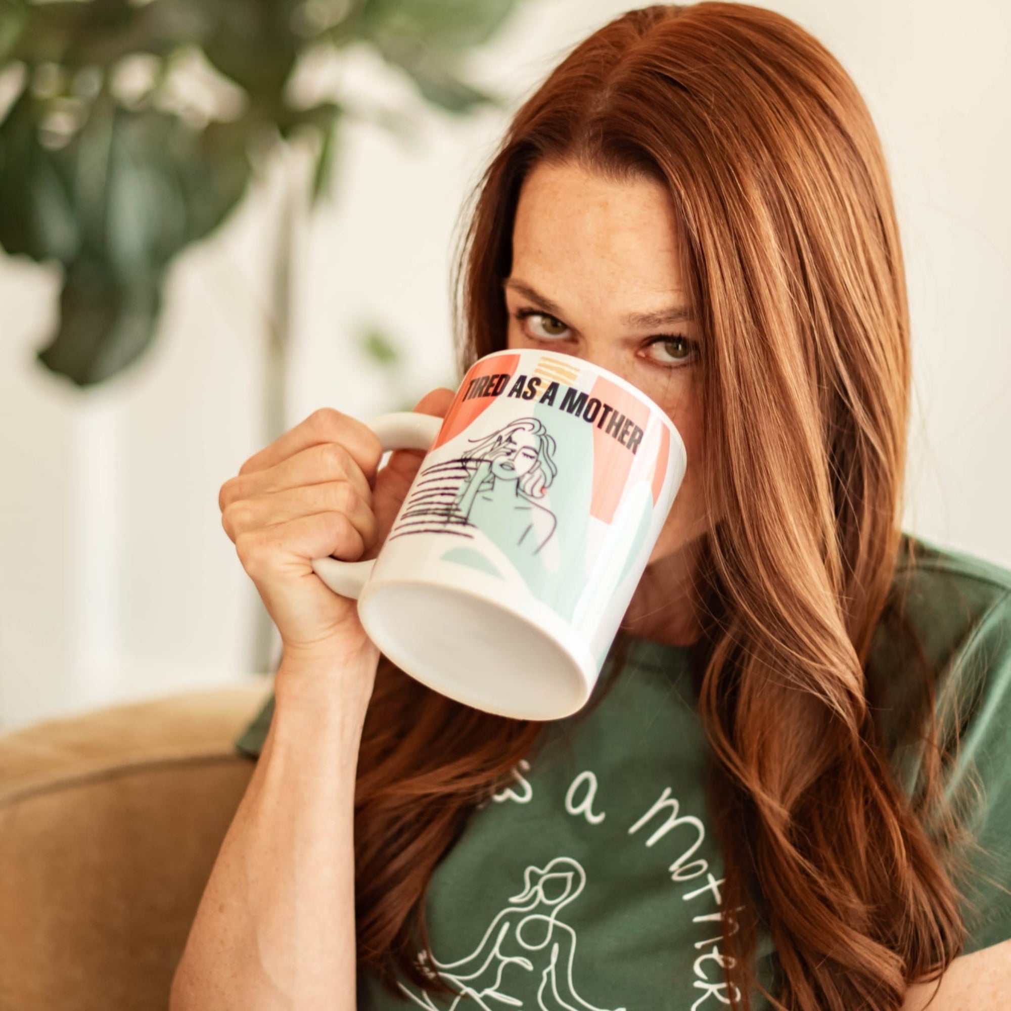 Woman sips from an oversized colorful mug that says 'Tired as a Mother' with exhausted woman line art design