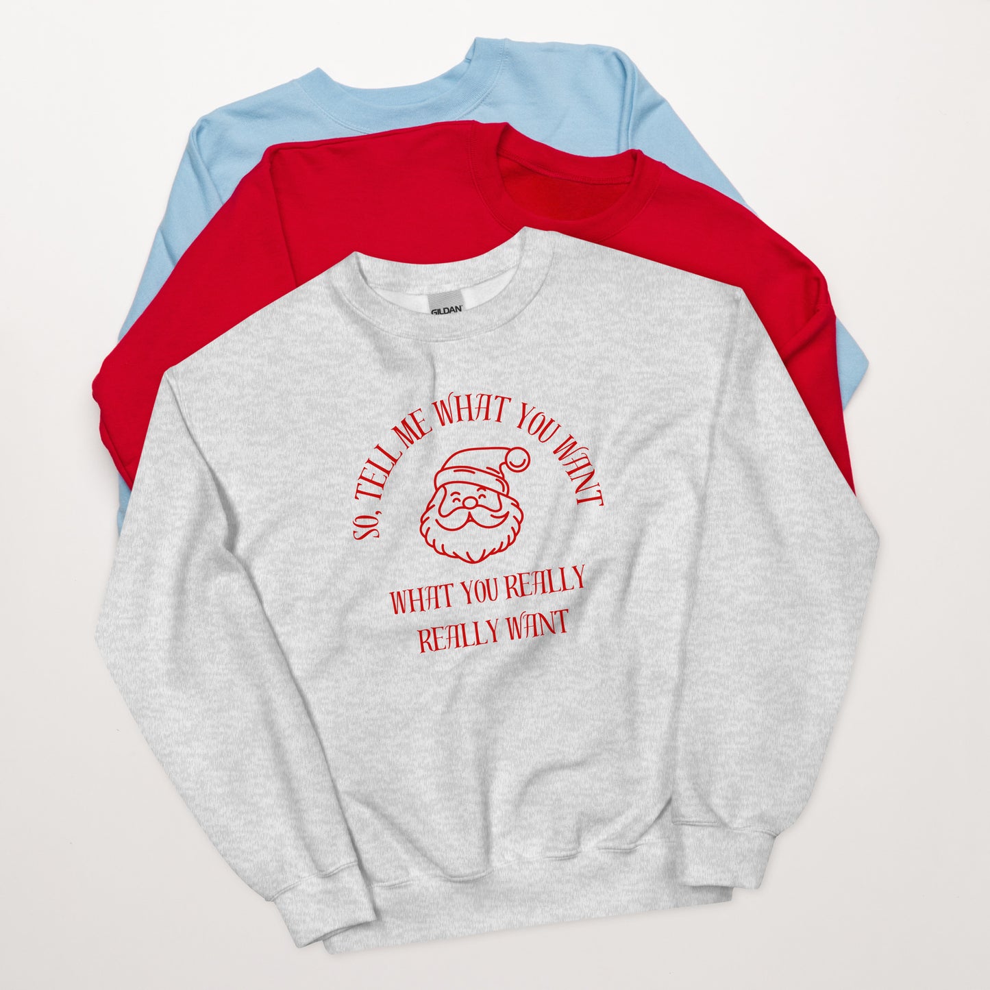 Gray and red crewneck sweatshirt featuring Santa's face and text that reads "So Tell Me What You Want What You Really Really Want," playfully referencing the Spice Girls song while incorporating holiday humor. mockup