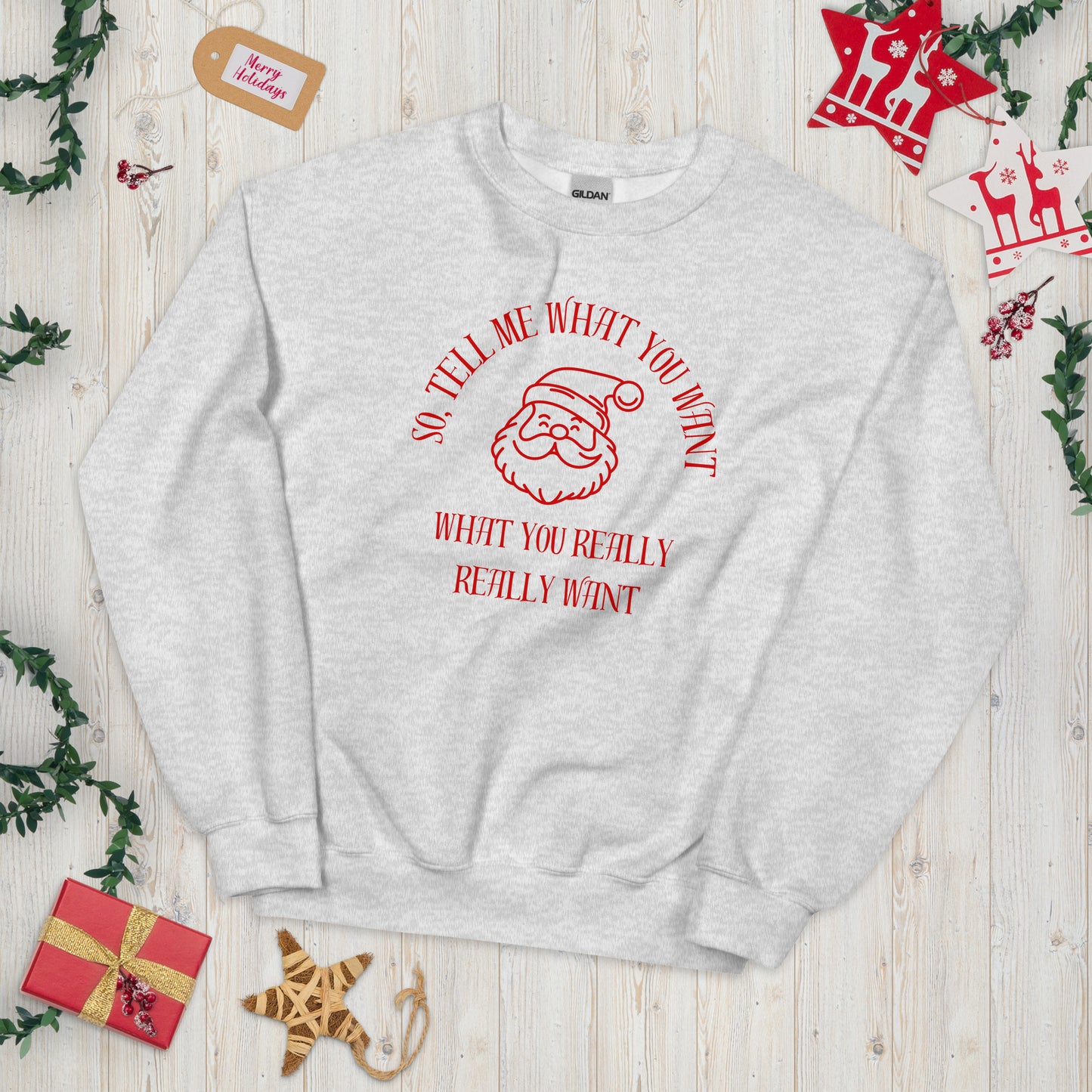 Festive crewneck sweatshirt featuring Santa's face and text that reads "So Tell Me What You Want What You Really Really Want," playfully referencing the Spice Girls song while incorporating holiday humor.