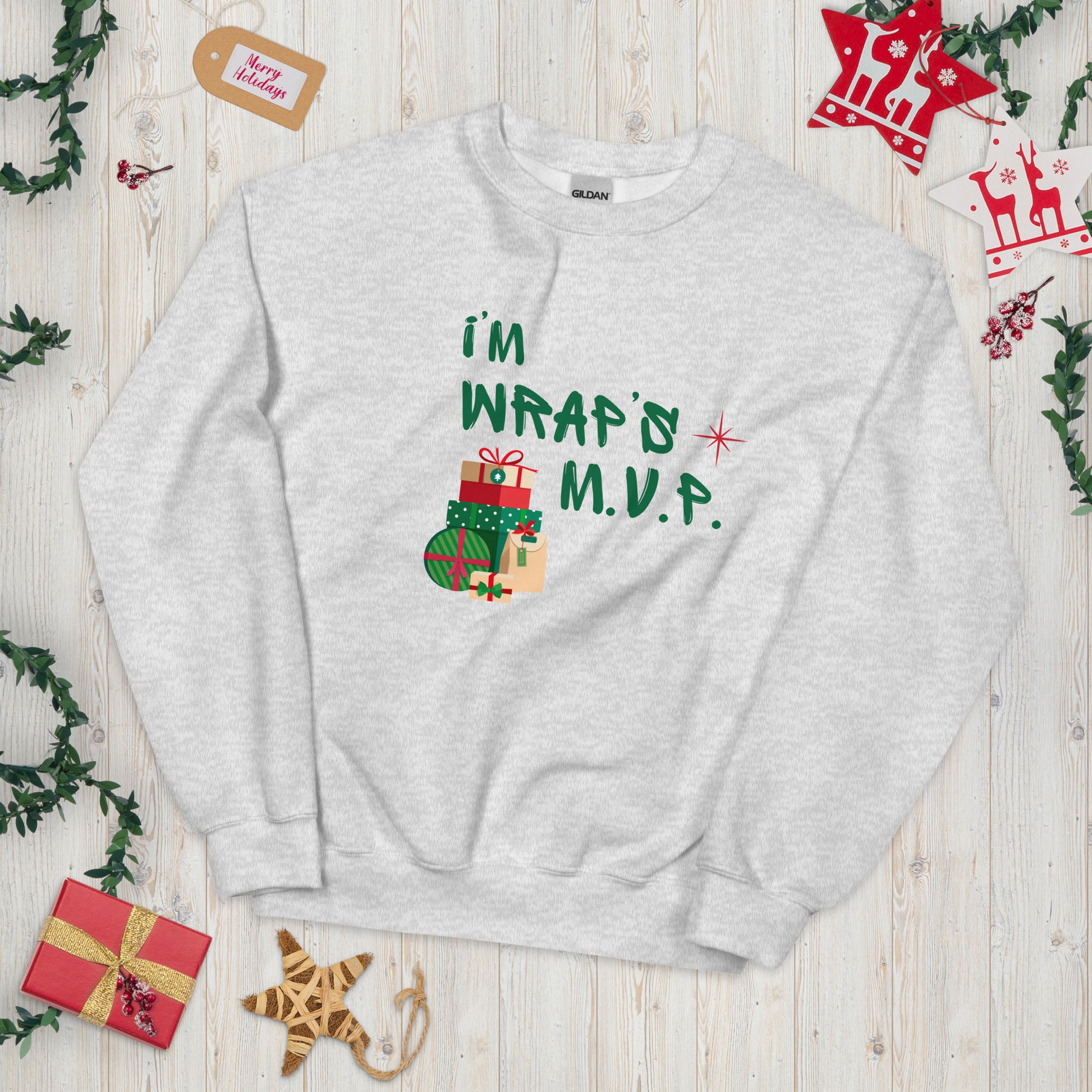 Heather Gray crewneck sweatshirt with green text reading 'I'M WRAP'D M.V.P.' and festive gift icons. A humorous Christmas play on words for holiday gift-wrapping enthusiasts.