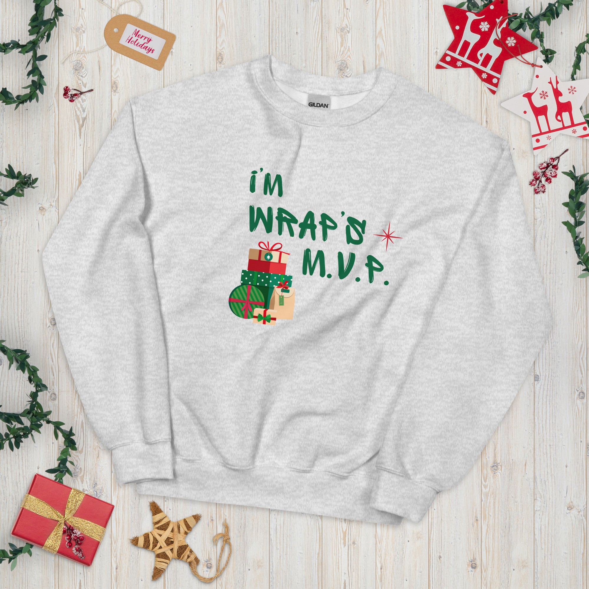 Heather Gray crewneck sweatshirt with green text reading 'I'M WRAP'D M.V.P.' and festive gift icons. A humorous Christmas play on words for holiday gift-wrapping enthusiasts.