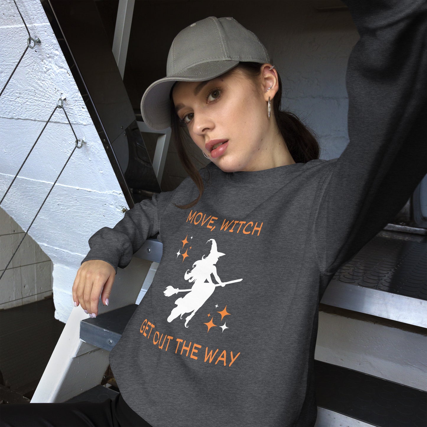 Woman wears gray Halloween sweatshirt with the white silhouette of a witch on a broomstick. The shirt says "Move, Witch Get out the way".