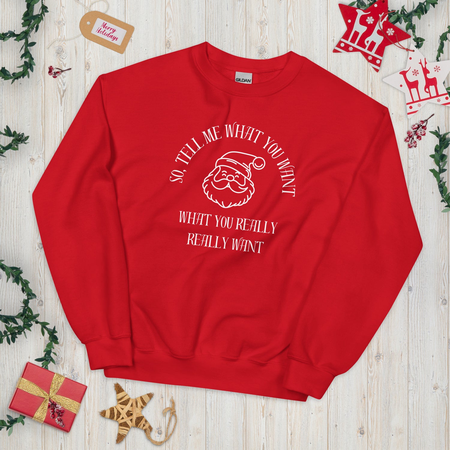 Festive red crewneck sweatshirt featuring Santa's face and text that reads "So Tell Me What You Want What You Really Really Want," playfully referencing the Spice Girls song while incorporating holiday humor.