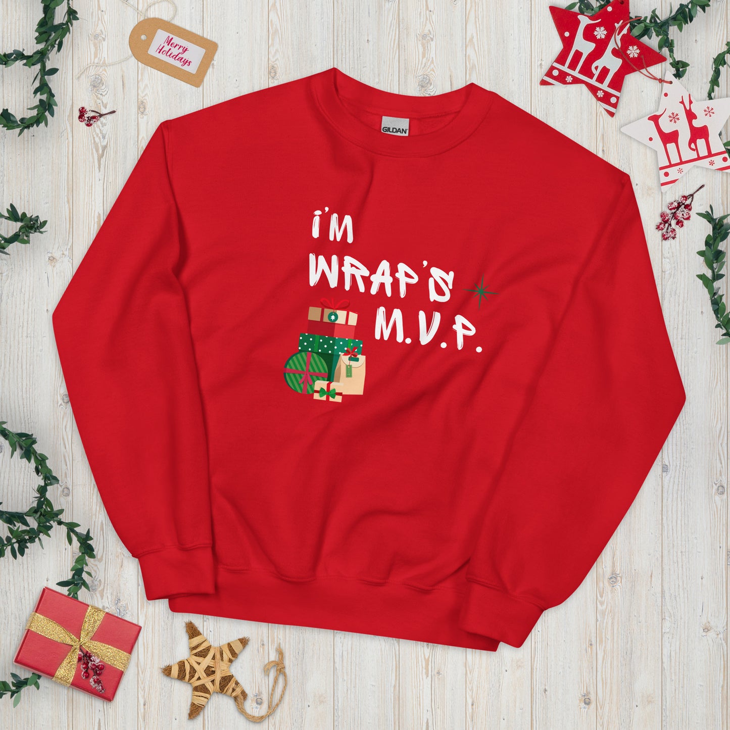 Bright red crewneck sweatshirt with white text reading 'I'M WRAPs M.V.P.' and festive gift icons. A humorous Christmas play on words for holiday gift-wrapping enthusiasts.