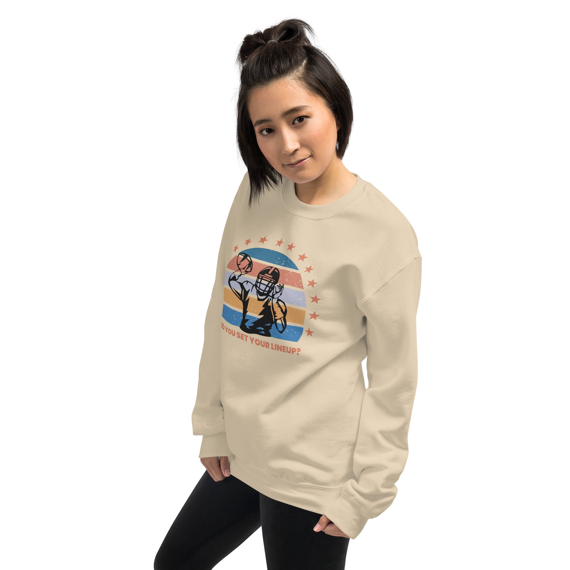 Young woman with short hair wears a fantasy football sweatshirt that reads "Did you set your line up?" The sweatshirt has a silhouette of a quarterback about the throw a football with a distressed backdrop of yellow, blues, and light pink and a star border.