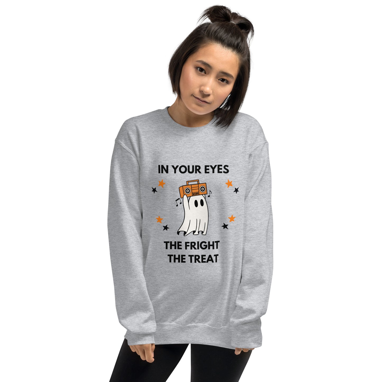 Woman with short dark hair wears a Halloween sweatshirt featuring a ghost holding an orange boombox overhead, Say Anything style. The shirt reads "In your eyes - The Fright, The Treat."