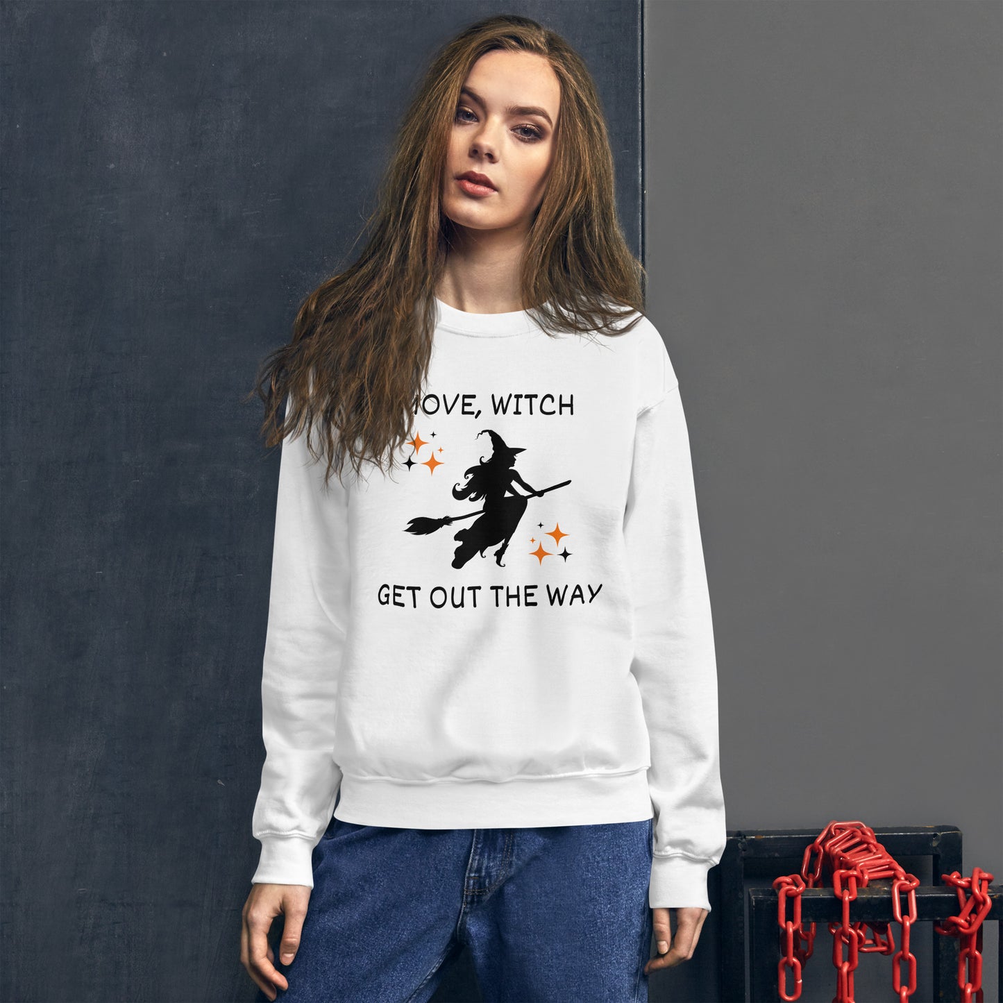 Woman wears white Halloween sweatshirt with the silhouette of a witch on a broomstick. The shirt says "Move, Witch Get out the way".