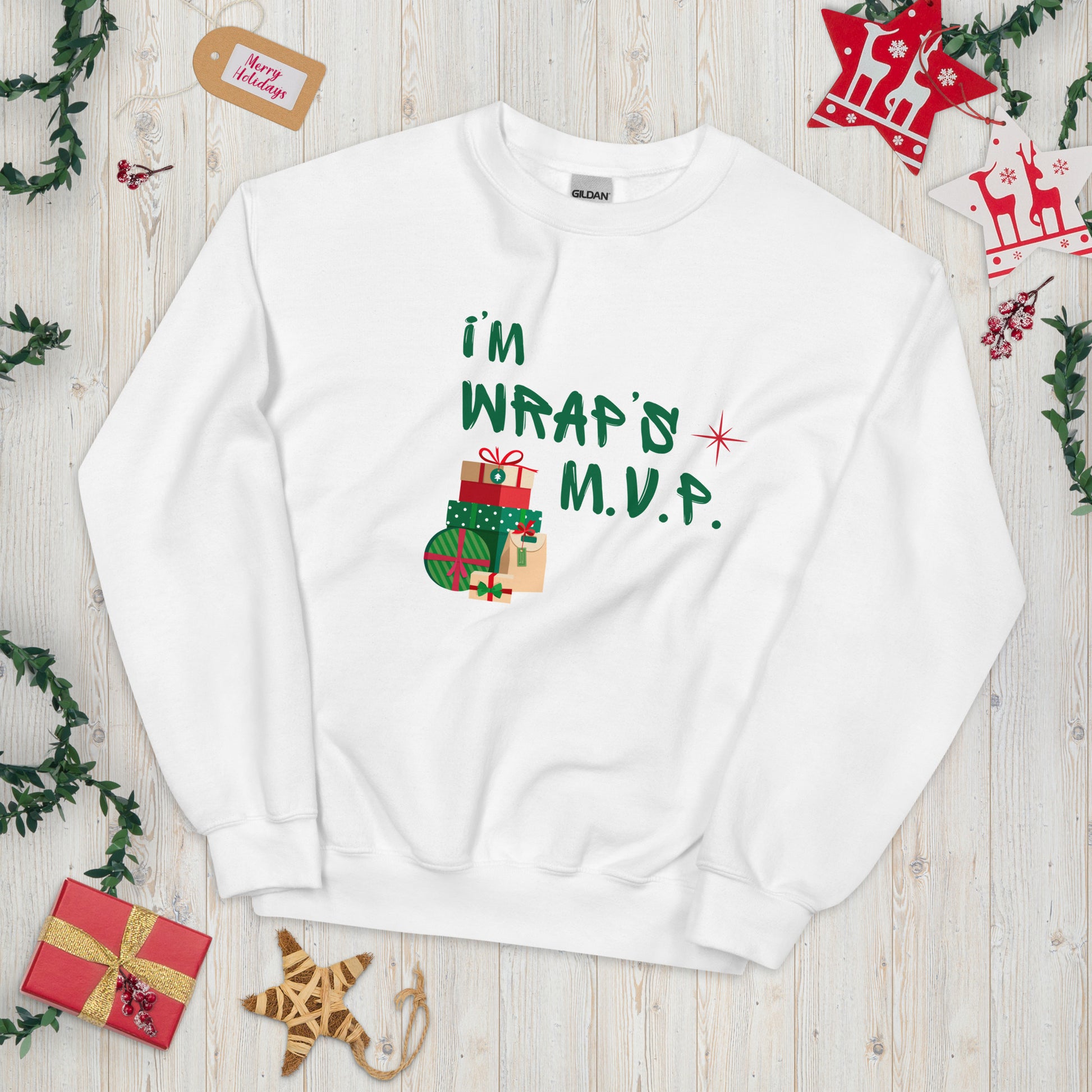 White crewneck sweatshirt with green text reading 'I'M WRAPs M.V.P.' and festive gift icons. A humorous Christmas play on words for holiday gift-wrapping enthusiasts.