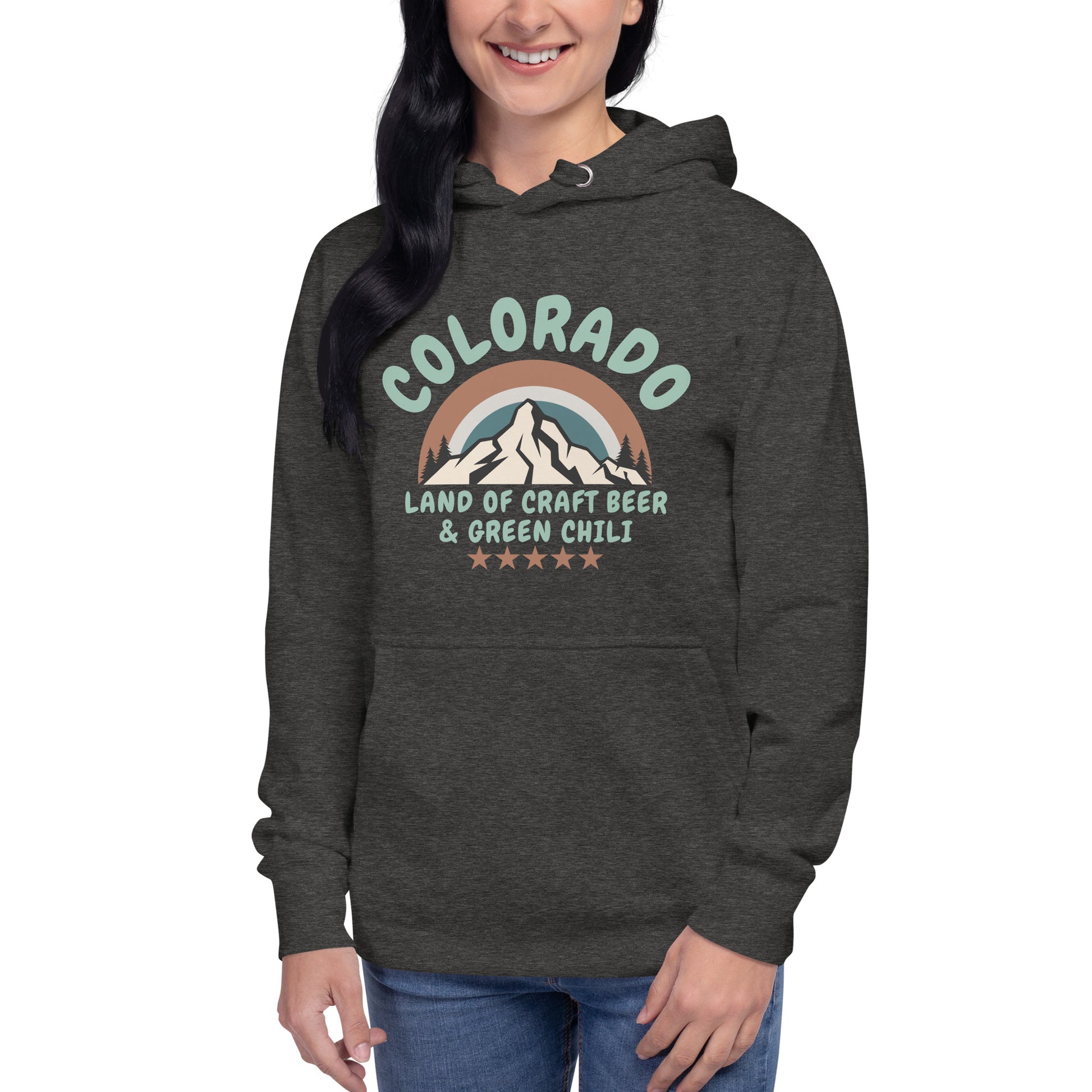 Smiling woman wears a charcoal gray hoodie and jeans. The hoodie says Colorado and shows a mountain scape, while also referencing craft beer and green chili