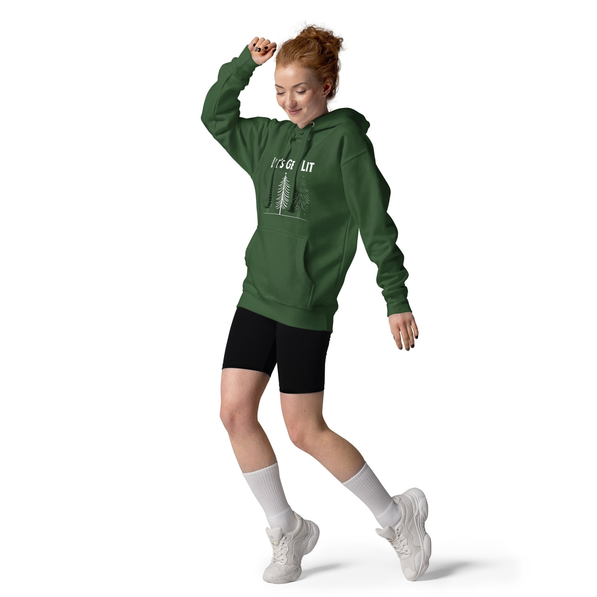 Dancing woman wears a green holiday hoodie  with the text "Let's Get Lit" printed on it, along with a graphic of three Christmas trees.