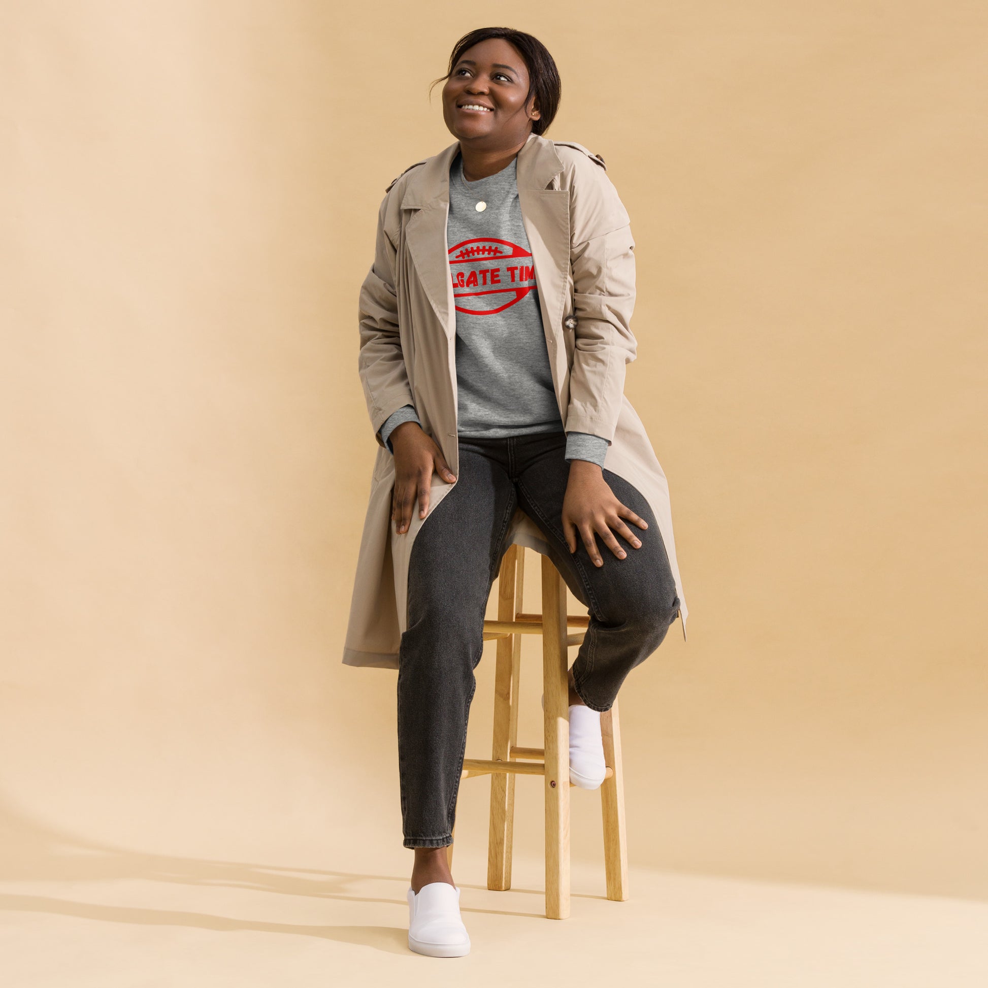 Woman wears a gray and red football sweatshirt. The charcoal gray crewneck displays a Chiefs red football graphic with the words "tailgate time" in a distressed font.