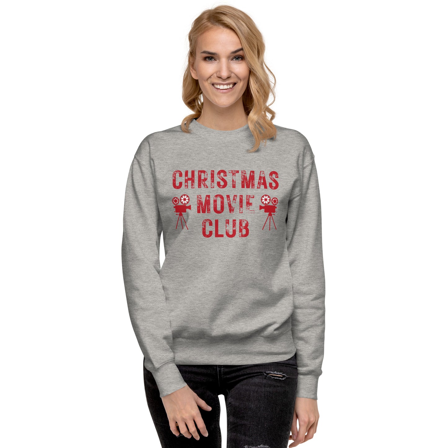 Woman models heather gray crewneck sweatshirt with distressed red text reading 'CHRISTMAS MOVIE CLUB', decorated with retro movie camera icons. Perfect for holiday movie marathons.