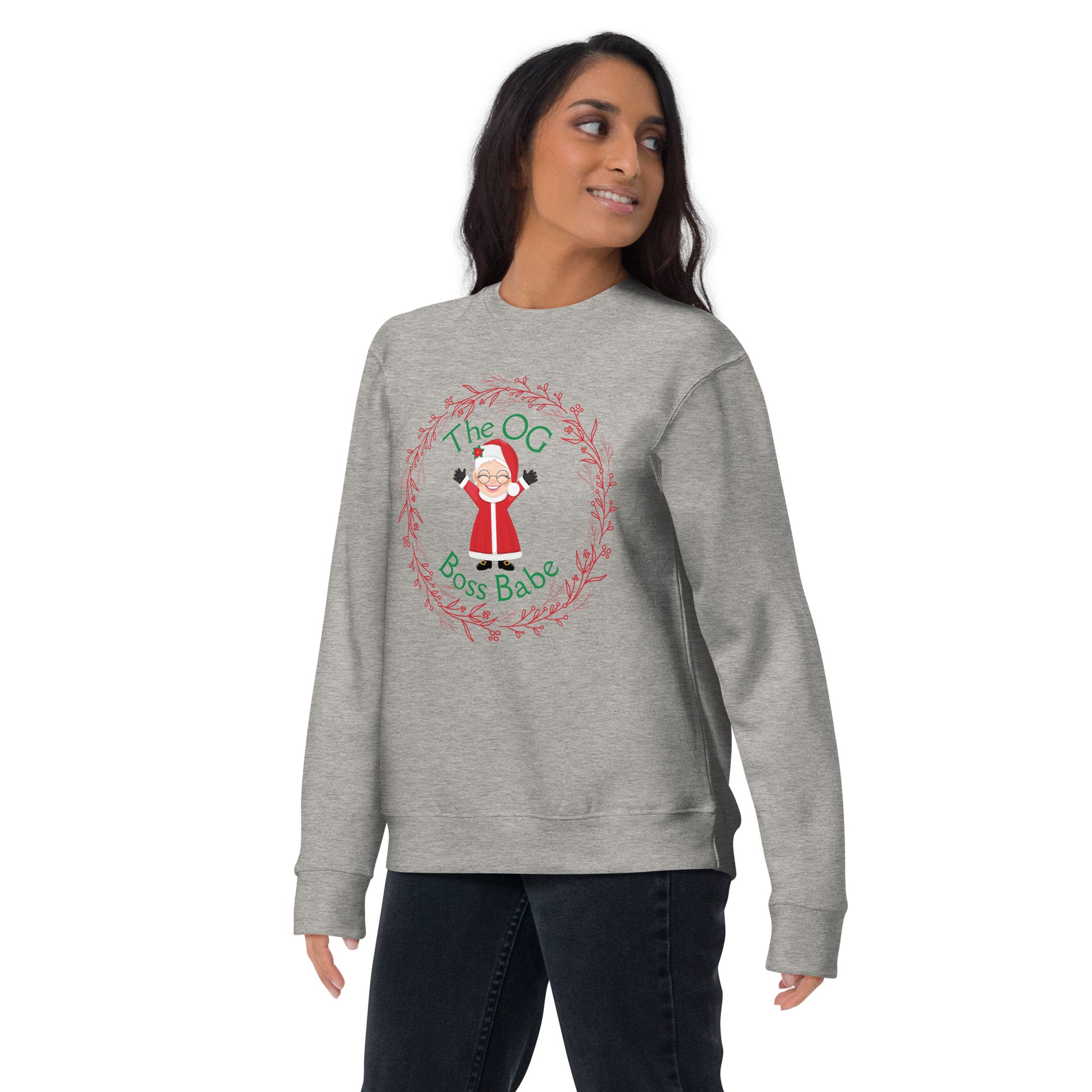 Smiling woman wears a festive crewneck sweatshirt with an image of Mrs. Claus that reads "The OG Boss Babe"