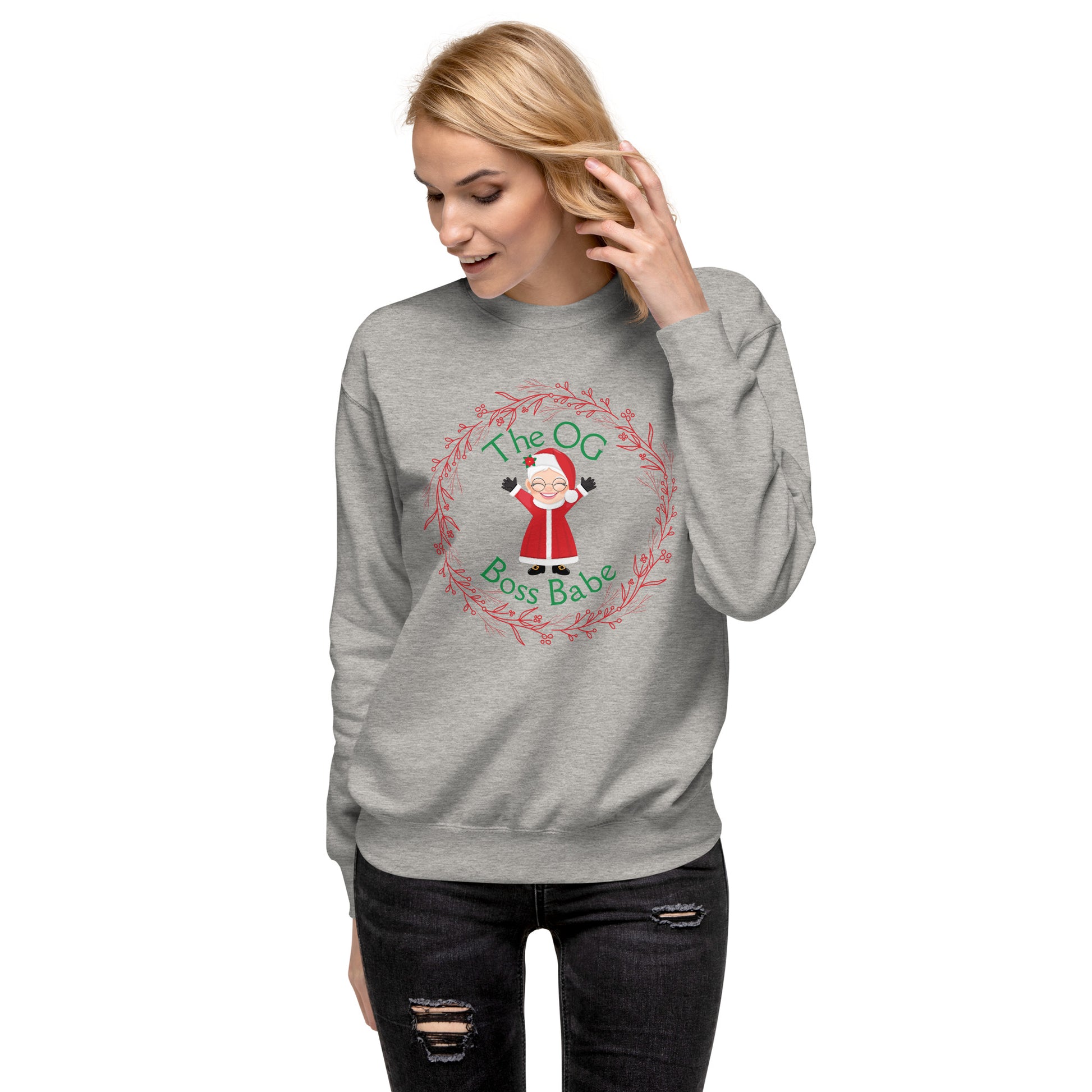 Smiling woman wears a festive crewneck sweatshirt with an image of Mrs. Claus that reads "The OG Boss Babe"