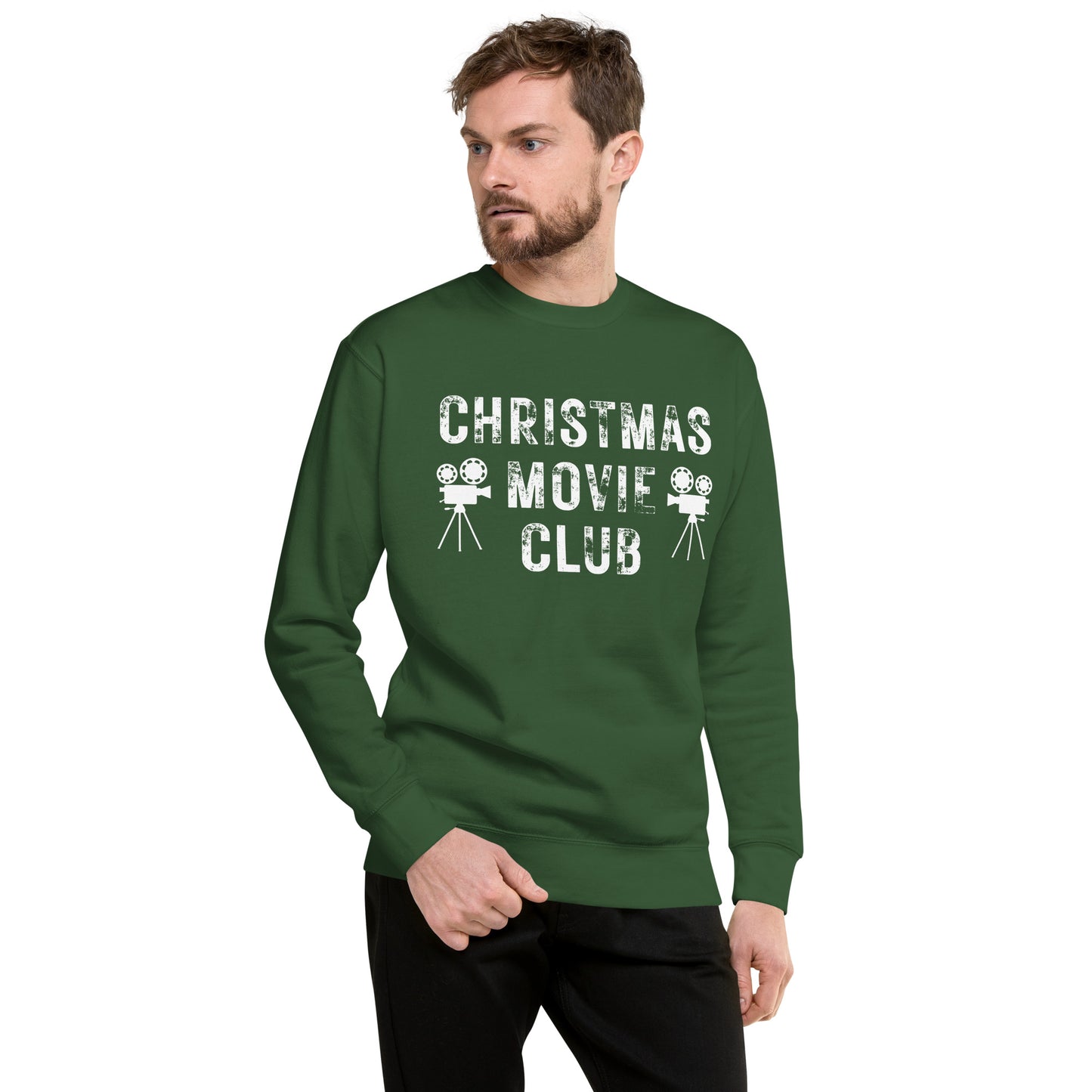 Man models orest green crewneck sweatshirt with distressed white text reading 'CHRISTMAS MOVIE CLUB', decorated with retro movie camera icons. Perfect for holiday movie marathons.