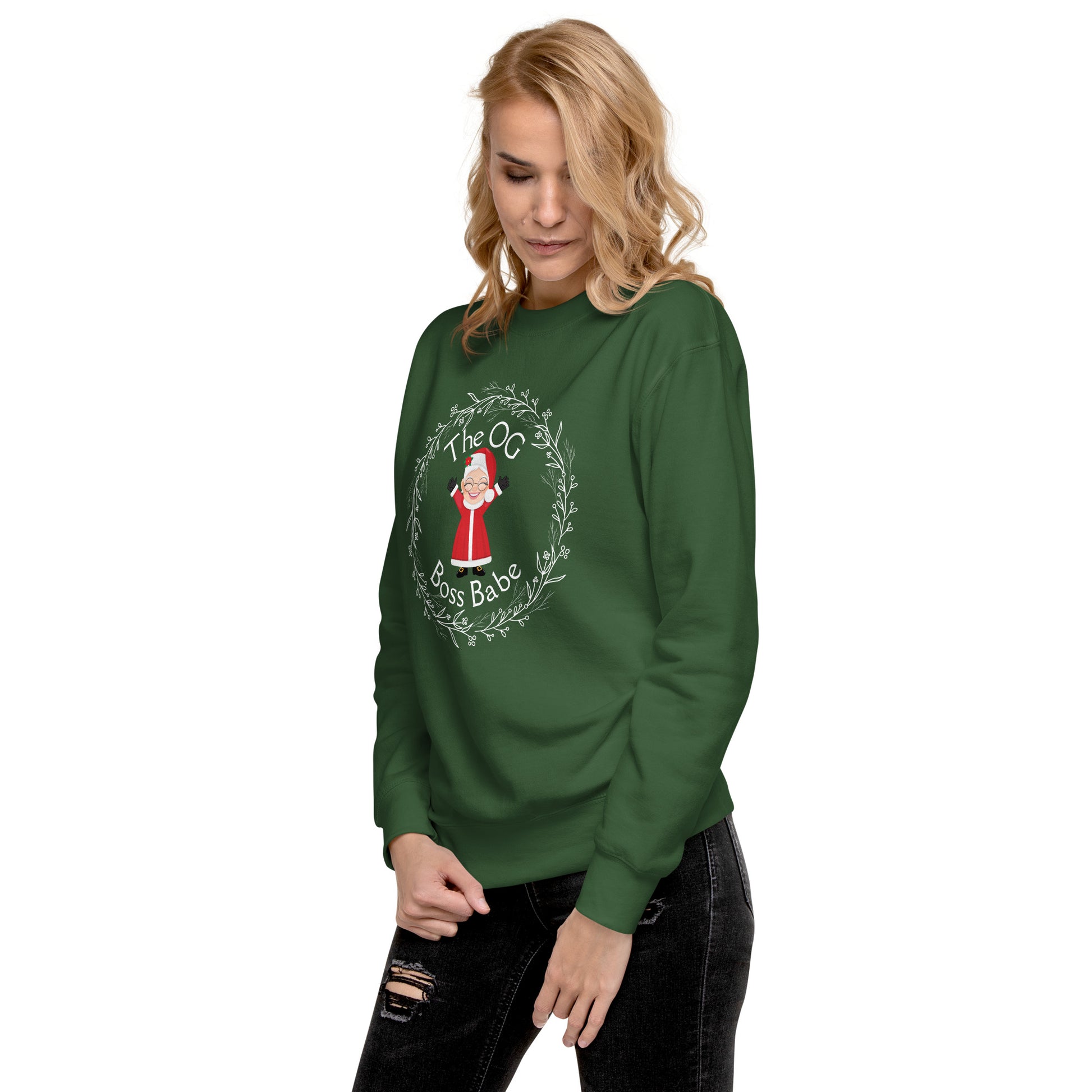 Woman wears a festive green crewneck sweatshirt with an image of Mrs. Claus that reads "The OG Boss Babe"