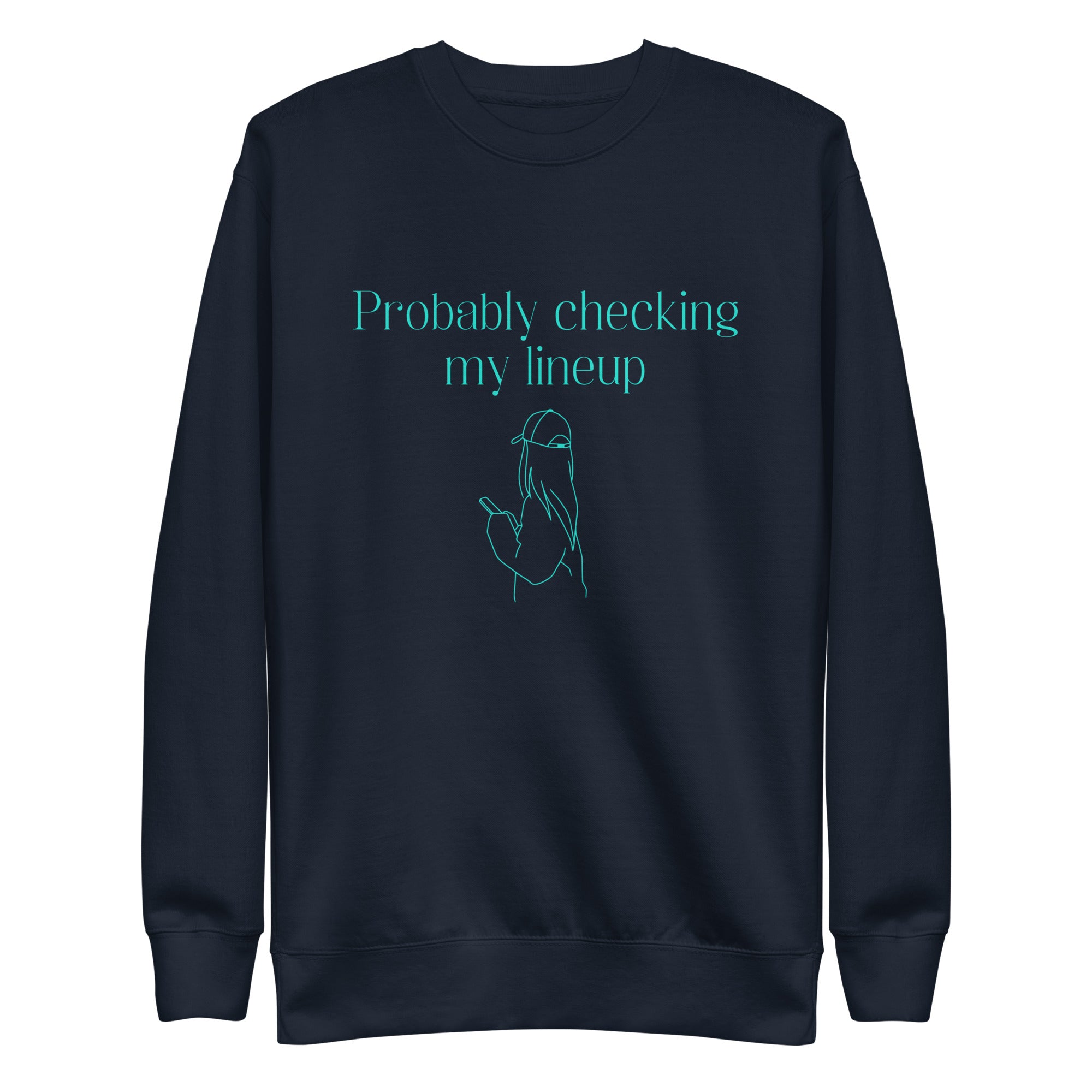 Navy crewneck sweatshirt with aqua line art and text shows a woman in a baseball cap checking her phone. The shirt reads "PROBABLY CHECKING MY LINEUP", a nod to women fantasy football managers.