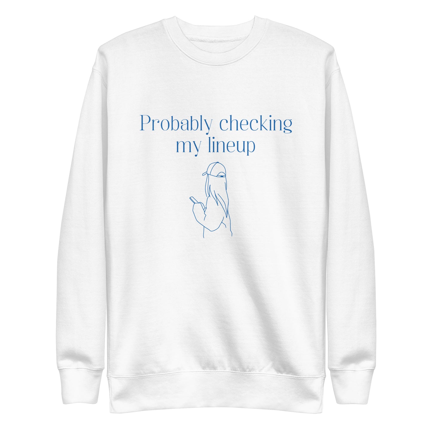 White crewneck sweatshirt with blue line art and text shows a woman in a baseball cap checking her phone. The shirt reads "PROBABLY CHECKING MY LINEUP", a nod to women fantasy football managers.