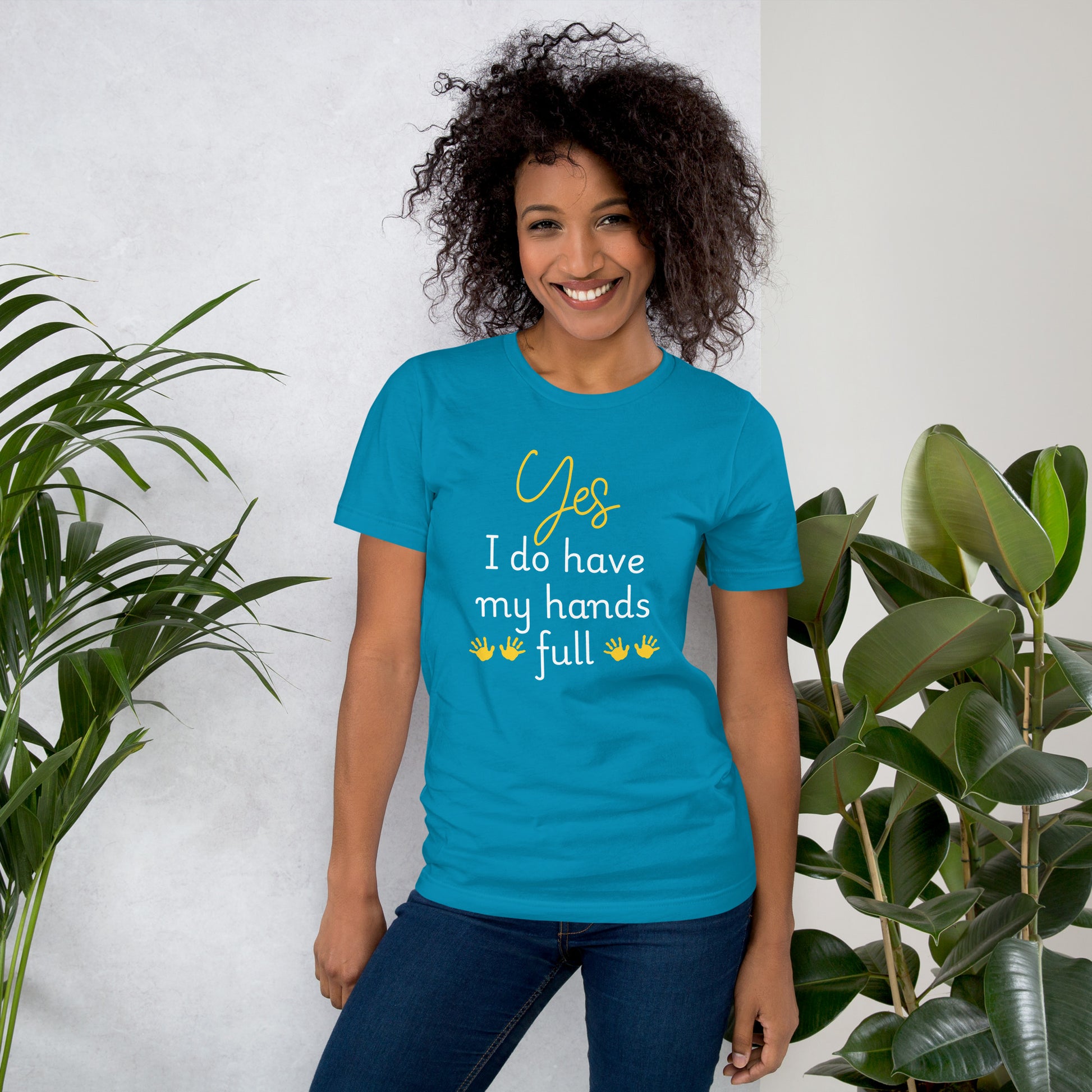 Smiling woman wears aqua blue tee that reads 'Yes, I do have my hands full' with two sets of child handprints.