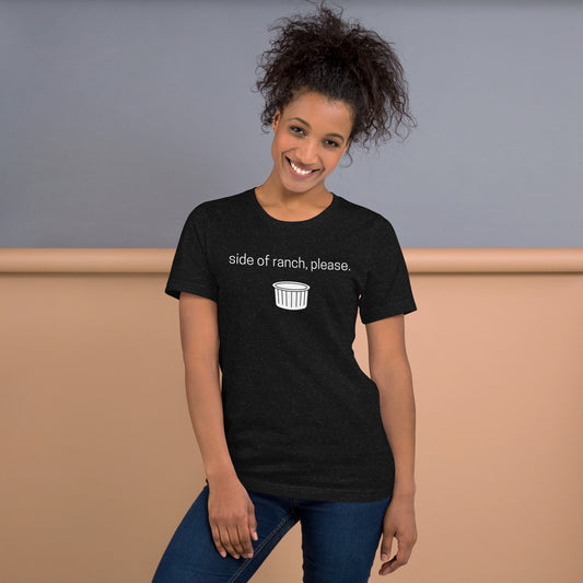 Smiling woman with curly hair wears a graphic tee that says "Side of ranch, please." accompanied by a white ramekin.  Her hair is pulled in  a ponytail and she wears jeans.