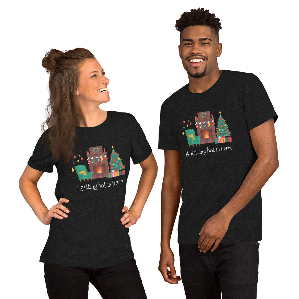 Couple wears matching holiday tee shirts that read "It's getting hot in herre" with a cozy Christmas living room design with decorations and a roaring fireplace.