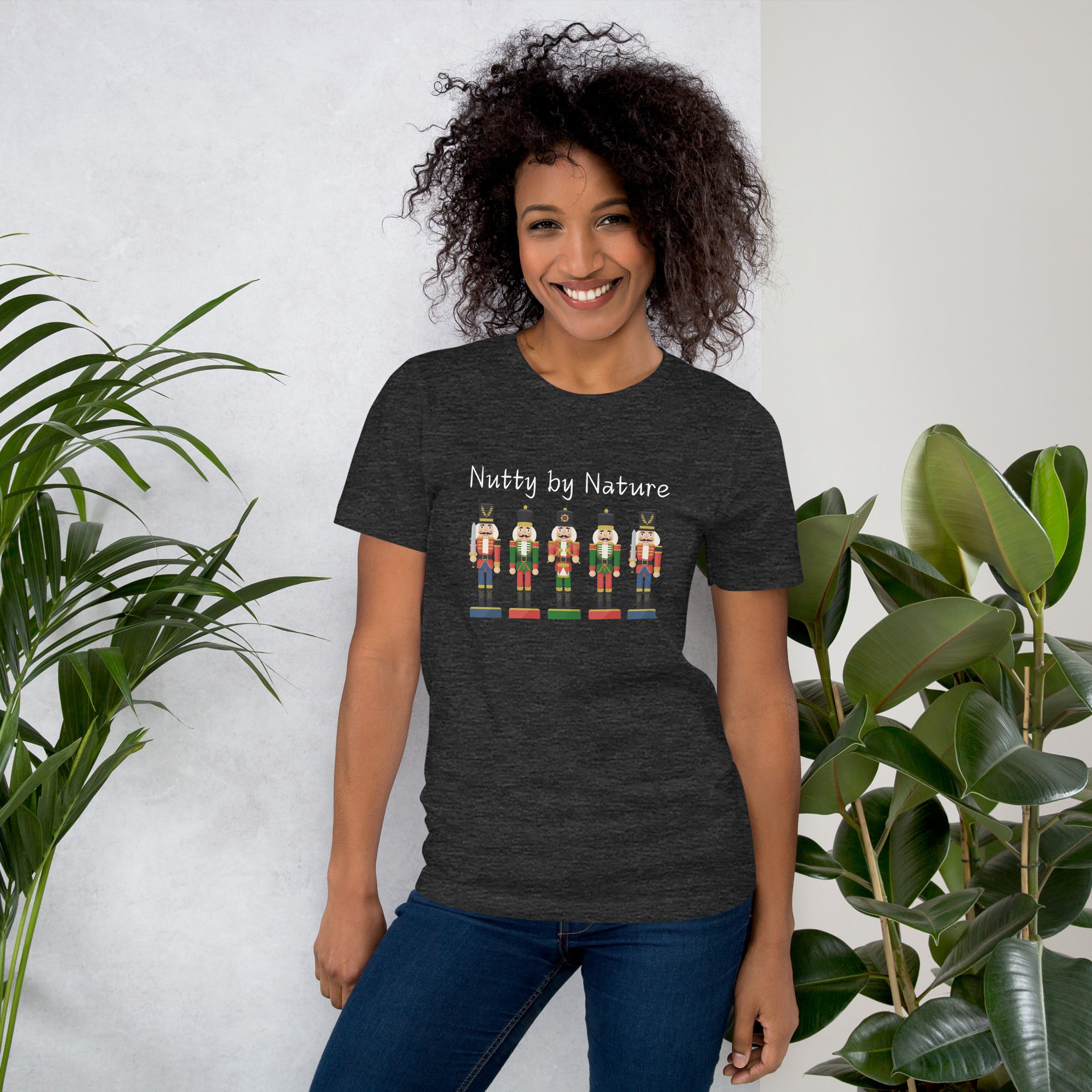 Woman wears a festive and playful holiday shirt featuring five nutcrackers and text that reads "Nutty by Nature"
