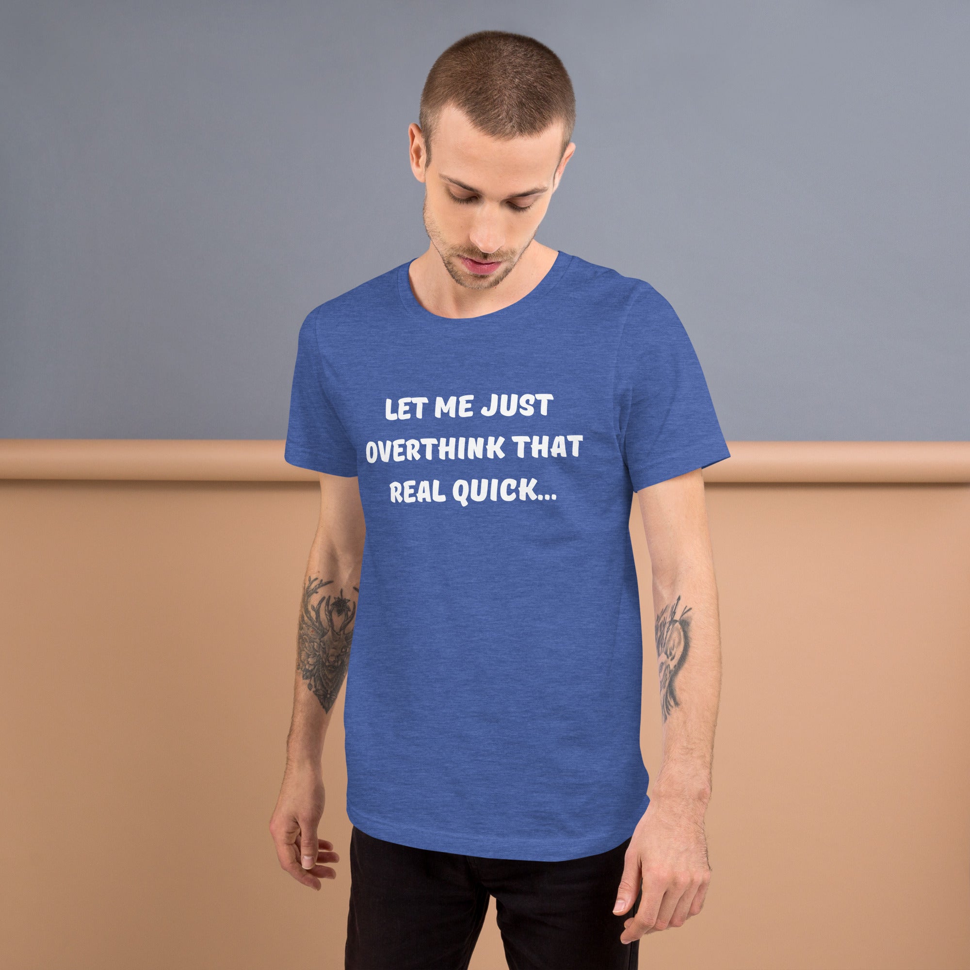 Young man with tattooed arms wears a blue tee shirt that reads "Let me just overthink that real quick..."