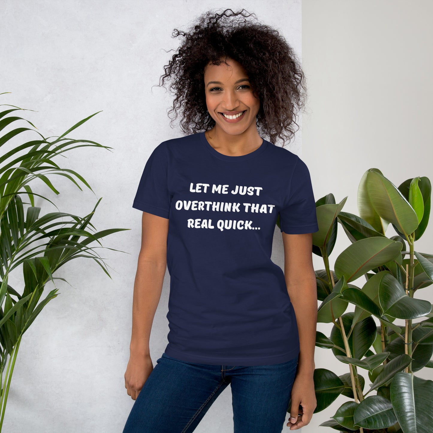 Smiling young woman with curly hair wears a navy blue tee shirt that reads "Let me just overthink that real quick..."