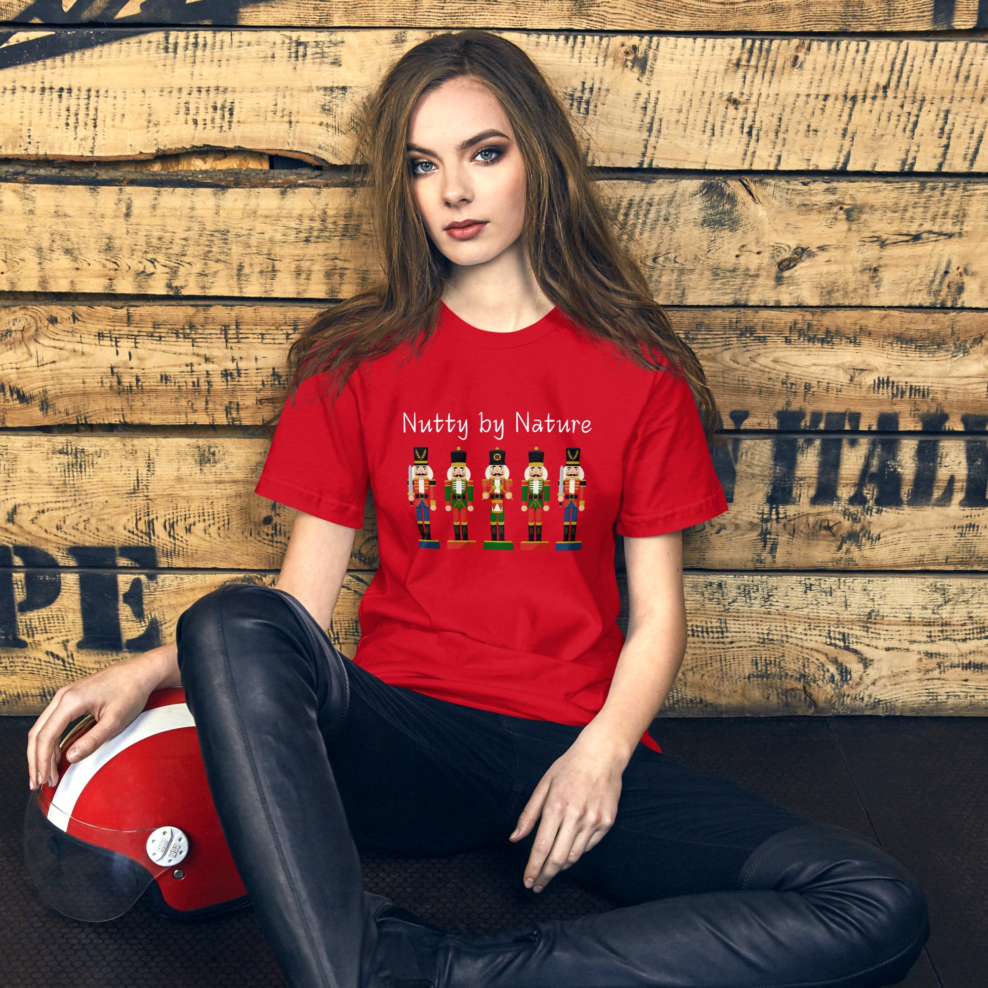 Woman wears a festive and playful holiday shirt featuring five nutcrackers and text that reads "Nutty by Nature"