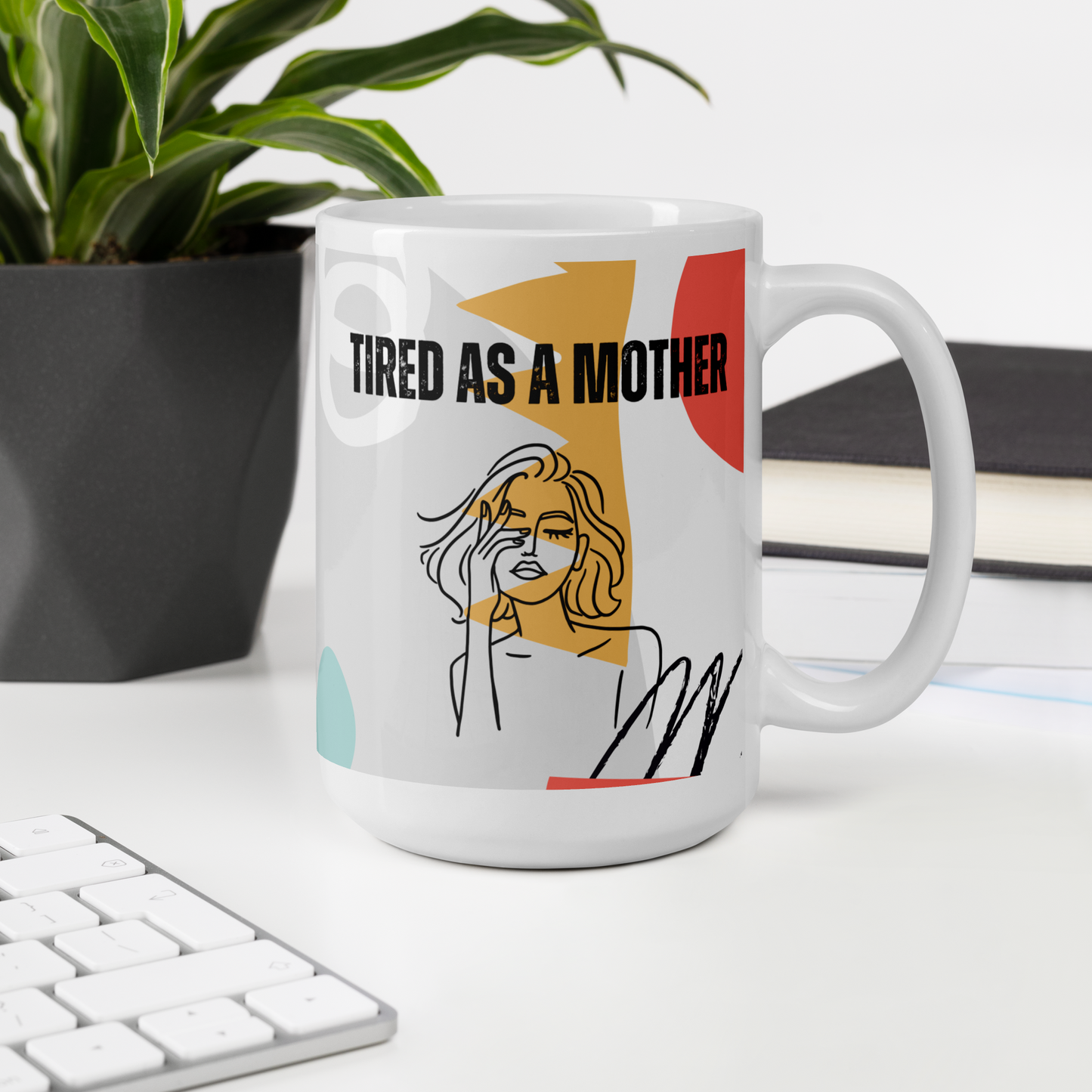 A colorful coffee mug that reads "TIRED AS A MOTHER" sits on a desk next to a plant and a keyboard. Under the text is line art of a woman with her eyes closed, rubbing one eye. A colorful background pattern includes mint, rosy pink, yellow, coral and black with shapes reminiscent of the 80s or early 90s.