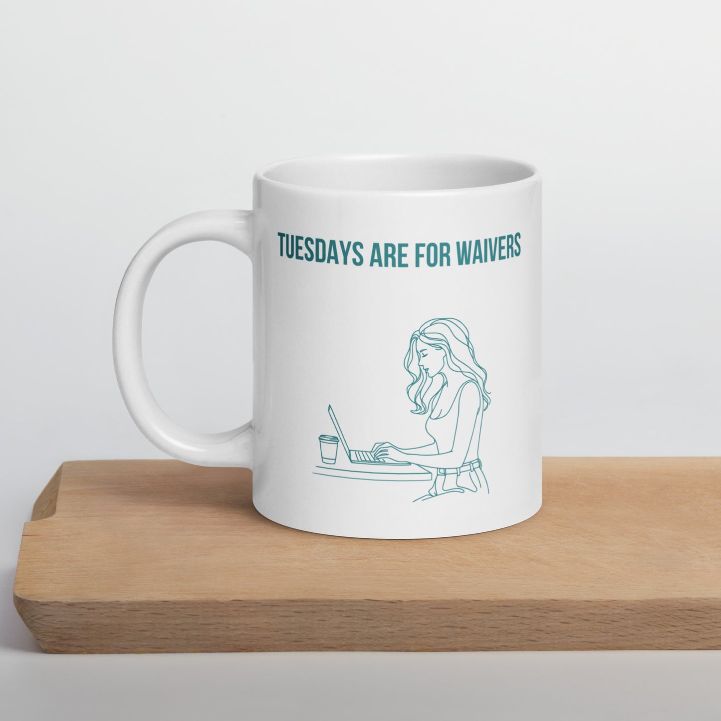 White ceramic mug sits on wooden shelf. It displays line art graphic of a woman working at a laptop and the text reads "TUESDAYS ARE FOR WAIVERS". It's a playful spin on Fantasy Football Managers who spend Tuesdays doing research and strategy before the waiver wire deadline.