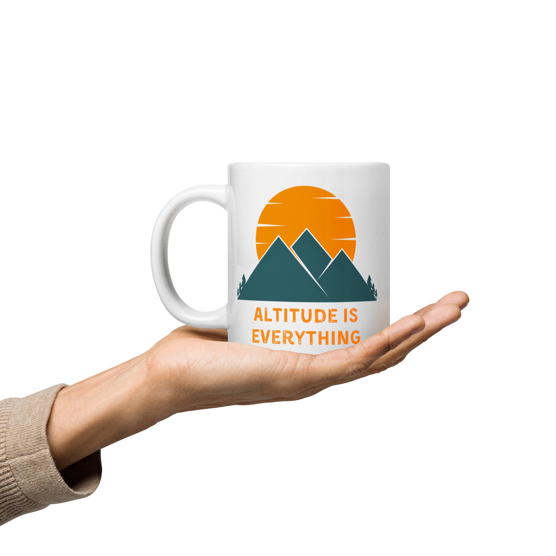 A white ceramic mug with a graphic design of mountains and a sunset, along with the text "ALTITUDE IS EVERYTHING" rests on someone's palm.