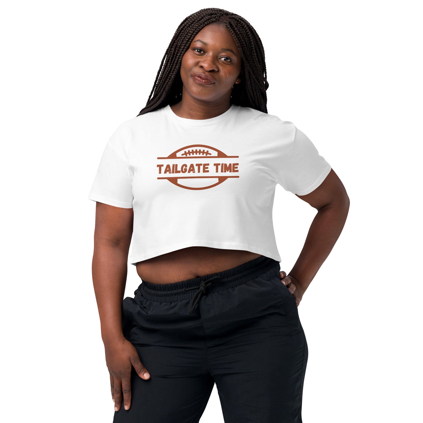 Young woman wears a football crop top and athleisure pants. The crop top has a football with words "Tailgate Time" in distressed lettering.