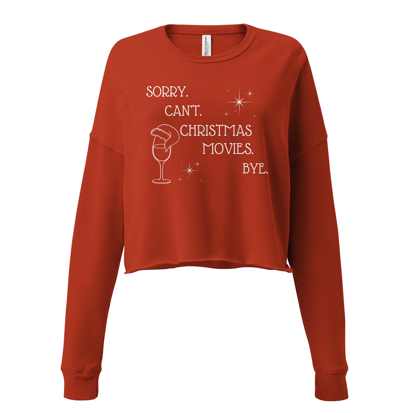 Festive red cropped sweatshirt reads "Sorry. Can't. Christmas Movies. Bye." It's accompanied by a wine glass topped with a Santa hat and star details.