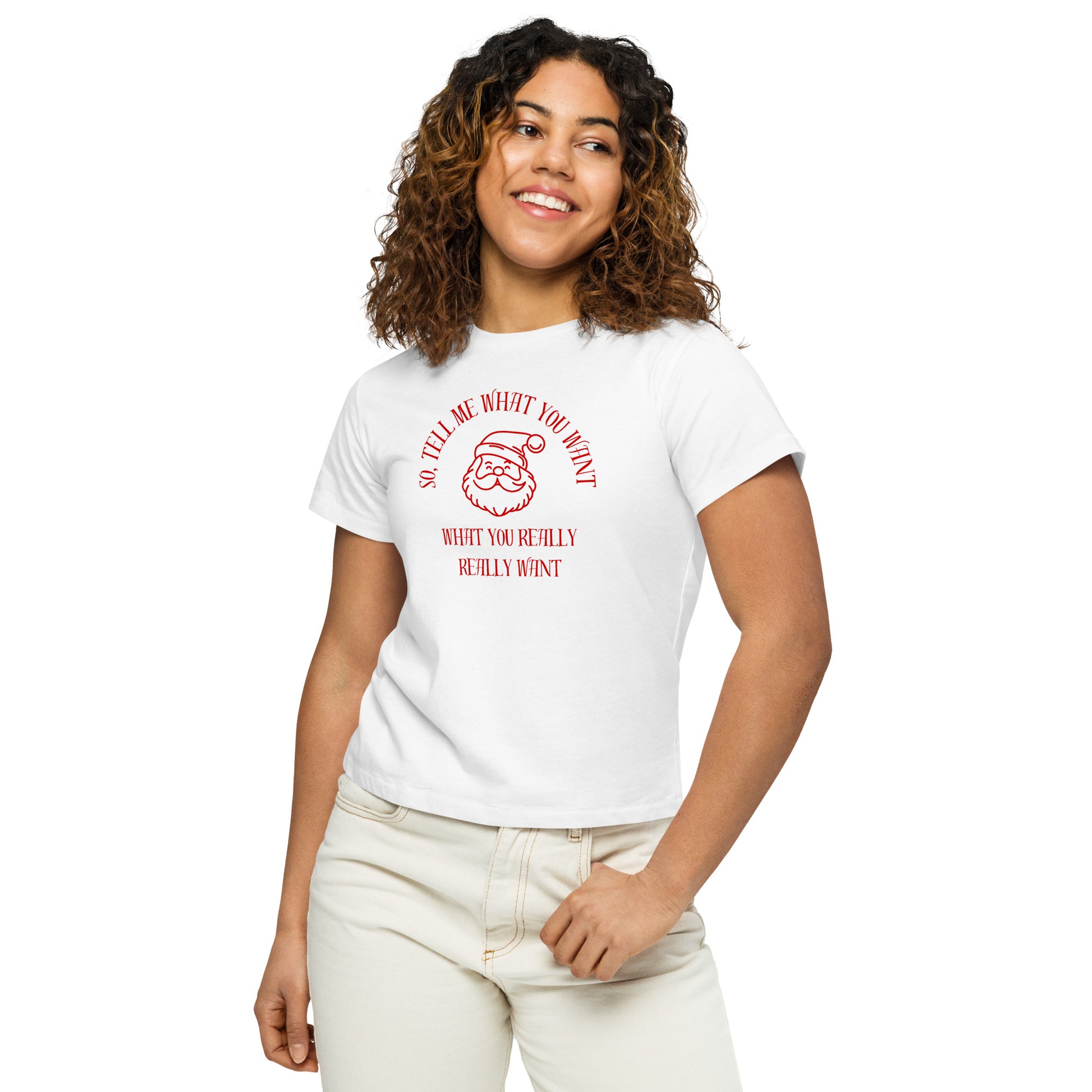 A woman models a fitted white mid-length t-shirt featuring Santa's face and the text "So Tell Me What You Want What You Really Really Want" in red, perfectly hitting at the waistline of her pants.