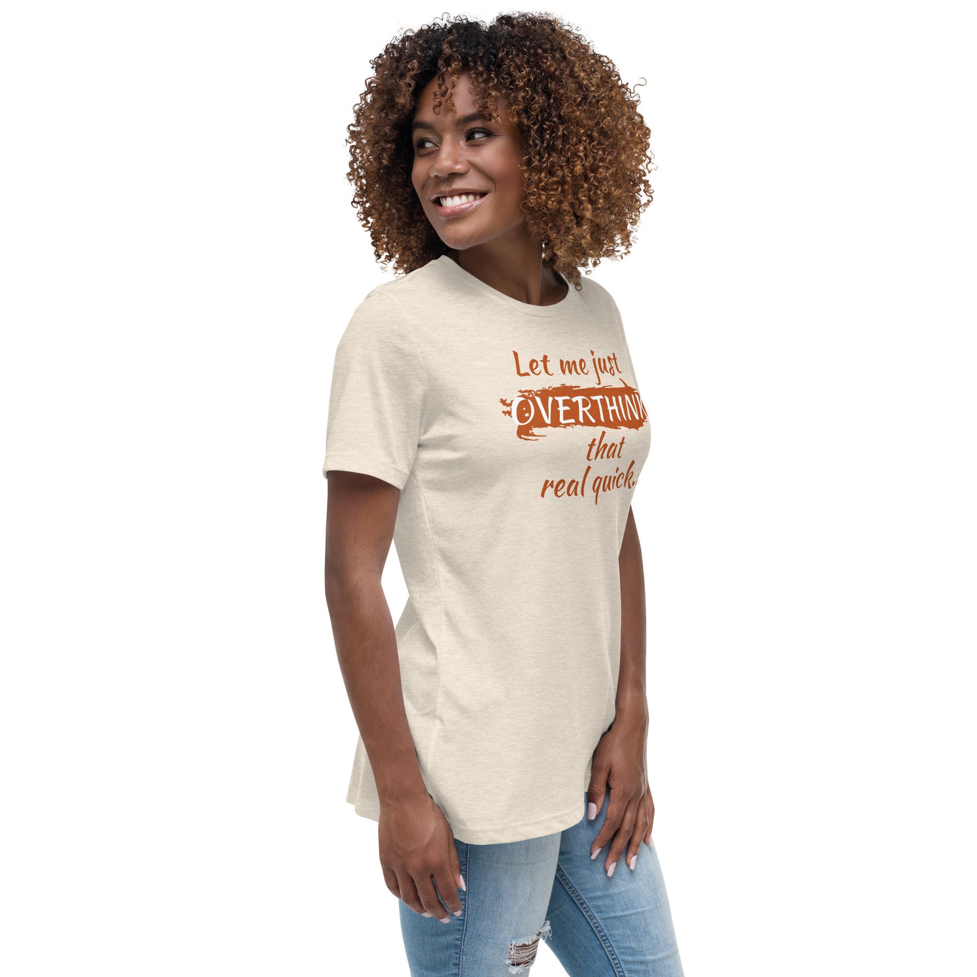 Woman wearing a cream colored graphic tee that says "Let me just overthink that real quick" in burnt orange font — funny overthinking shirt for women.