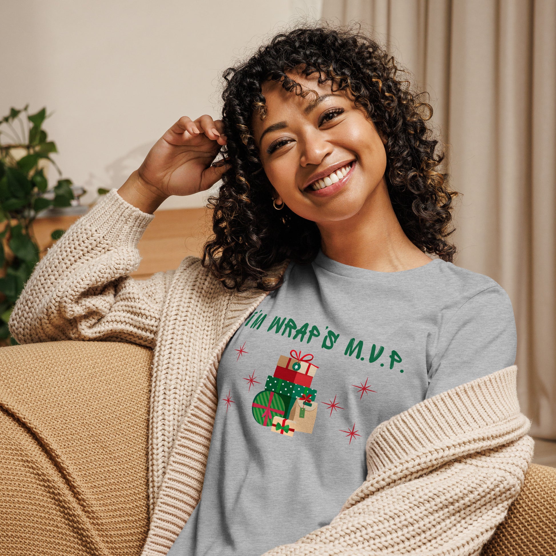 Woman wears a festive holiday tee that reads "I'm wrap's MVP" next to a stack of neatly wrapped holiday gifts and red stars.