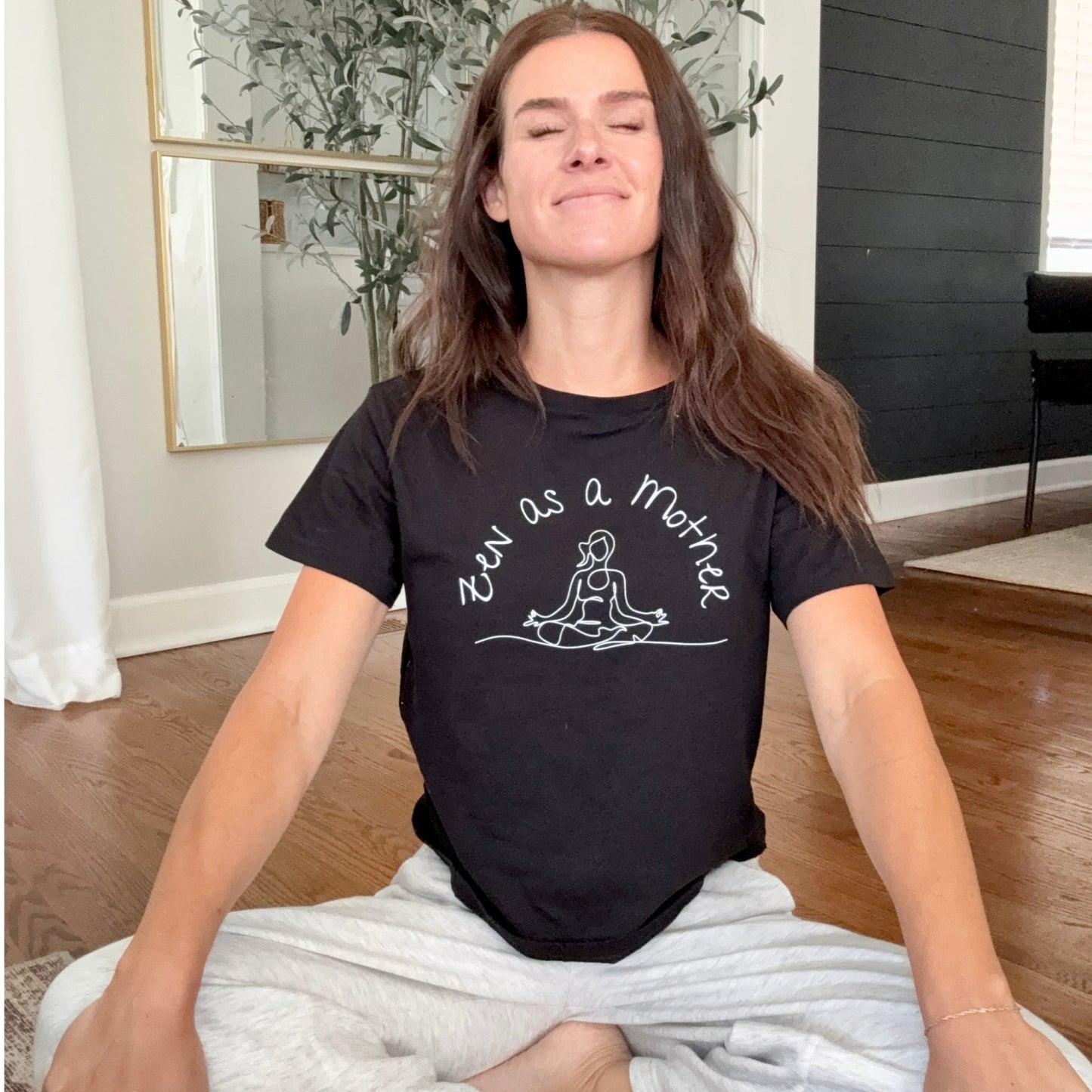 Woman sits peacefully in lotus position wearing Zen as Mother t-shirt in black from Jade Street Market